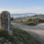 Antico cippo di pietra accanto a una strada di campagna italiana / Old stone milestone beside an Italian country road